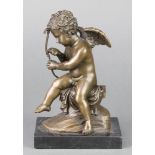 A bronze seated figure of Cupid raised on a rectangular marble base 8"
