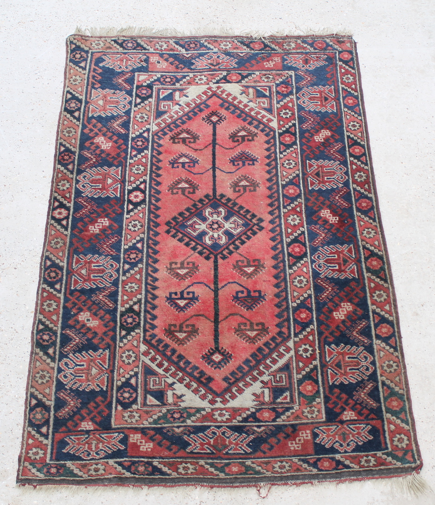 A red and white ground Persian rug with diamond medallion to the centre and stylised tree of life