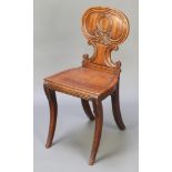 A Regency mahogany hall chair with shaped back and solid seat raised on sabre supports The left hand