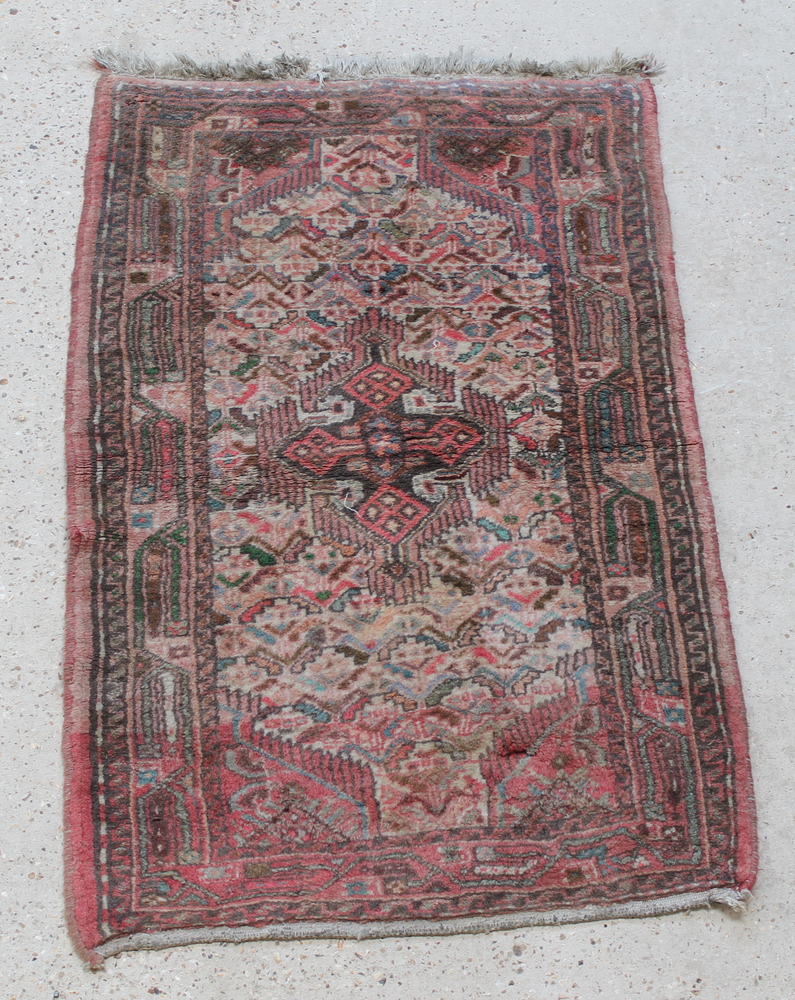 A pink ground Persian rug 49" x 31"There is some light staining and the fringe is missing to 1 end