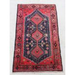 A red and blue ground Persian rug with diamond shaped medallion and having 3 diamond medallions to