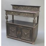 A Victorian carved and ebonised oak buffet with raised back fitted 2 drawers above a recess, the