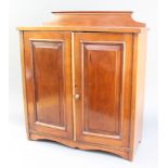 An Edwardian mahogany table top cabinet with raised back, fitted a shelf enclosed by a panelled