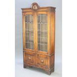 An Art Nouveau oak bookcase with arched top, fitted adjustable shelves enclosed by lead glazed