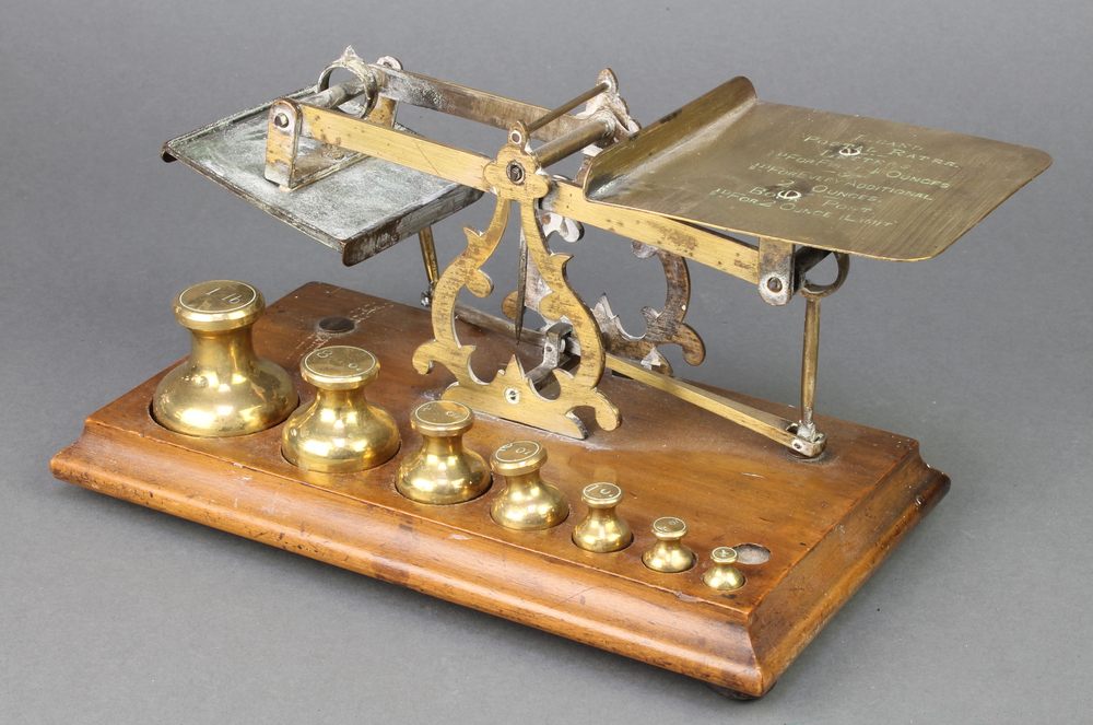 A pair of 19th Century brass letter scales raised on a mahogany stand with 7 weights - 1lb, 8 ozs, 4