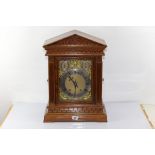 A LATE 19TH CENTURY ARCHITECTURAL CASED OAK BRACKET CLOCK, the rectangular brass dial with