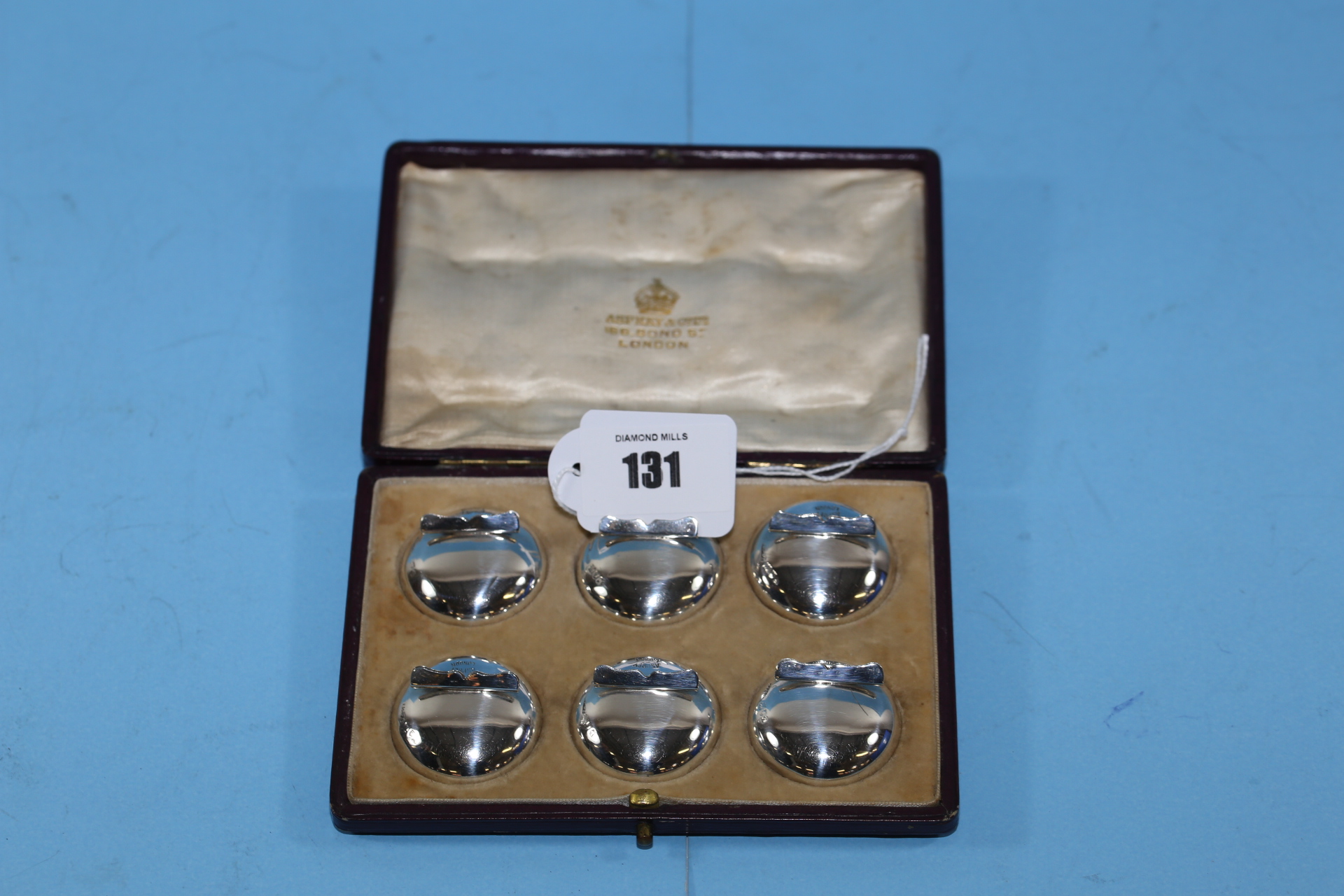 A SET OF SIX GEORGE V CIRCULAR SILVER PLACE CARD HOLDERS, makers:- Asprey & Co, 166 Bond Street,