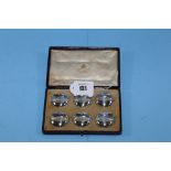 A SET OF SIX GEORGE V CIRCULAR SILVER PLACE CARD HOLDERS, makers:- Asprey & Co, 166 Bond Street,