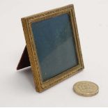 An early 20thC squared brass strutt / easel frame with pseudo Moroccan leather covered backing