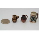 A collection of three miniature stoneware pieces to include a tankard and two jugs .