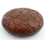 An oriental red carved cinnabar lacquer box and cover of squat circular form with peony decoration.