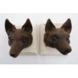 A pair of 19thC cast iron stylised fox masks on squared plinths.