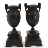 A pair of 19thC bronze and slate classical urns on squared tiered soccles 15" high