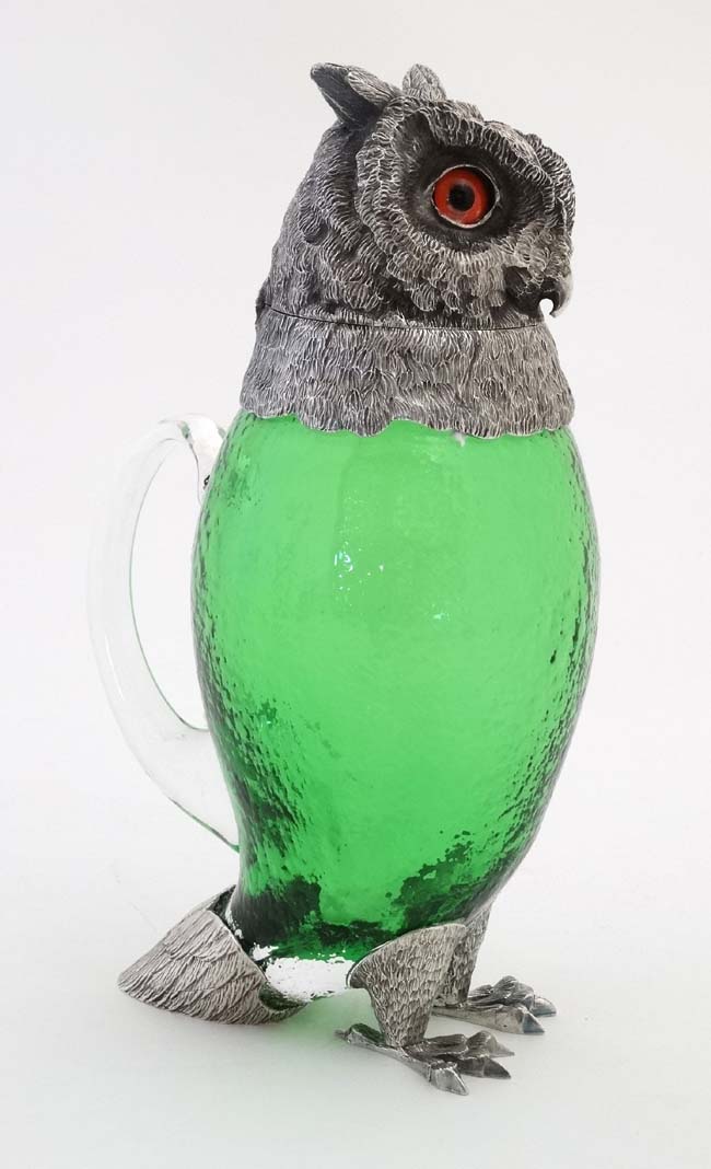 A late 20thC silver plate and green glass novelty claret jug in the form of an owl with glass eyes.