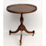 A 20thC Regency style mahogany circular tripod table with brass gallery.