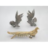 A pair of silver plate cast models of cockerels together with a brass model of a pheasant.