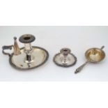 3 silver plated items comprising a tea strainer, short candlestick and a chamber stick.