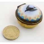 An early 20thC enamel and gilt decorated circular box with image of swallow amongst turquoise