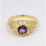 A silver gilt ring set with central amethyst set with numerous seed pearls to the openwork mount