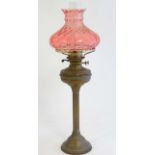 A 19thC brass oil lamp of reeded column form with cranberry glass shade and twin burners.