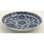 A Chinese blue and white dish decorated with peonies and chrysanthemums amongst scrolling leaves,