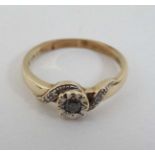 A 9ct gold ring set with central diamond flanked by chip set diamonds to shoulders