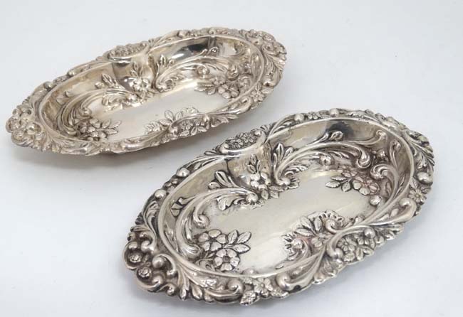 A matched pair of silver dishes with embossed floral and scroll decoration.