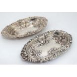 A matched pair of silver dishes with embossed floral and scroll decoration.