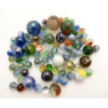 A collection of approximately 80 marbles, including cat's eye, iridescent ,