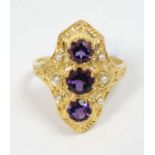 A silver gilt ring set with three amethysts flanked by seed pearls.