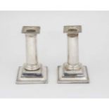 A pair of silver plate candlesticks the circular column on squared stepped bases with beaded