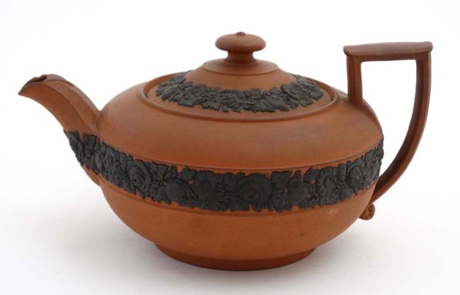 A 19thC Wedgewood '' Rosso Antico '' teapot with black basalt floral border decoration,