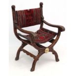 A 19thC carved oak X-framed open arm chair with Persian slung carpet seat and back 39 1/2" high