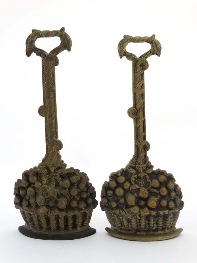 A pair of Georgian style cast brass and weighted iron door porters in the form of fruiting baskets