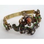 A late 19thC / early 20thC yellow metal bracelet with ornate decoration set with garnet like stones