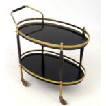 Art Deco : An oval tea trolley of brass frame, black wooden supports ,