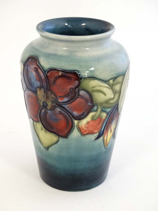 A mid 20thC Moorcroft '' Clematis '' pattern vase on a pale blue ground with tube lined decoration,