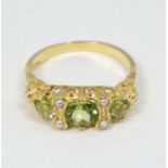 A Silver gilt ring set with three graduated peridot and 6 seed pearls.