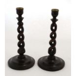 A pair of early 20thC oak open double twist candlesticks with circular stepped bases.