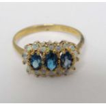 A silver gilt ring set with three topaz coloured stones bordered by opal like stones.