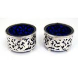 A pair of silver salts with pierced decoration and blue glass liners.