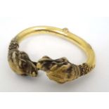 A 19thC Etruscan style yellow metal bangle formed bracelet with lions head finial set with ruby