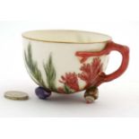 A 19thC teacup decorated in pink and green with seaweed and coral on a white ground,