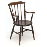 A c.1900 circular elm seated stick back elbow chair.