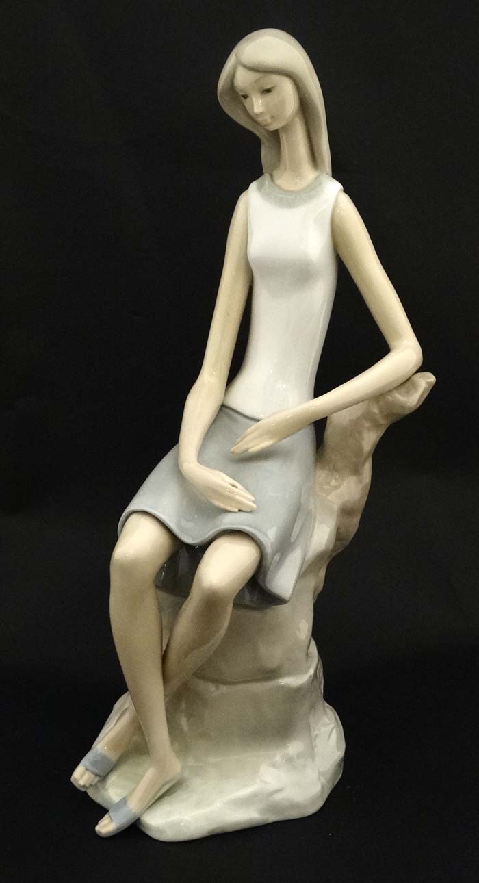 A Lladro figure modelled as a lady sat upon a rock, bears factory stamp to base.