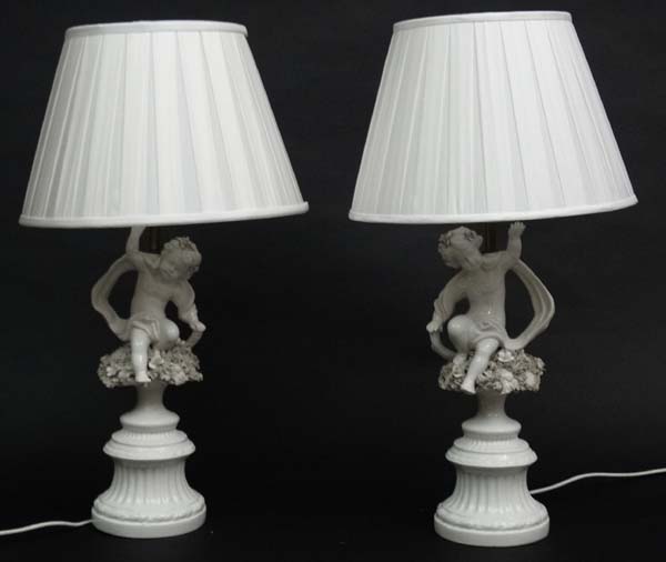A pair of handed white ceramic table lamps with silk shades, in the form of cherubs with scarves. - Image 3 of 4