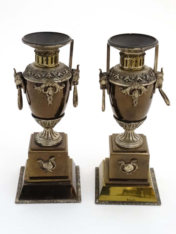 A pair of Egyptian Revival 19thC bronzed pedestal urns with loop handles.