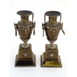 A pair of Egyptian Revival 19thC bronzed pedestal urns with loop handles.