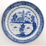 A Chinese blue and white plate decorated to central well with boats upon a lake in a mountainous
