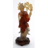 A Chinese carved agate figure of a woman holding flowers. on stand.